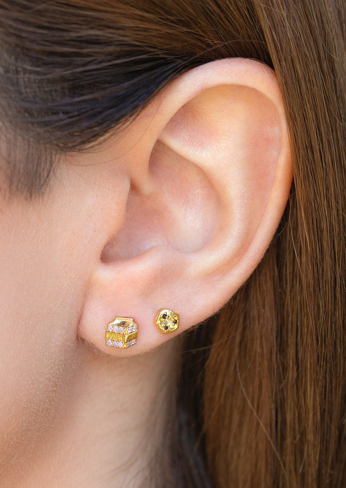 A pair of gold stud earrings in mismatched milk and cookies.