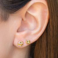 2: A pair of gold stud earrings in mismatched milk and cookies.