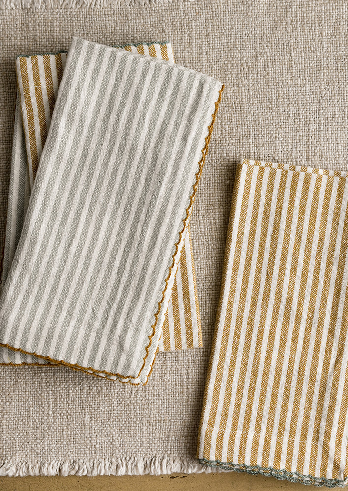 A set of four striped dinner napkins in grey-blue and brown stripes.