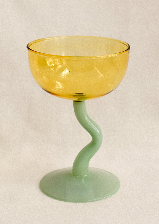 Glass with yellow bowl and green stem on a beige background