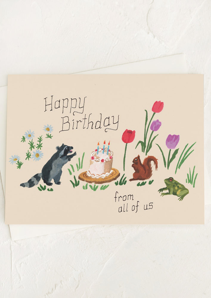 A card with illustrations of animals standing around a birthday cake, text reads "Happy birthday from all of us".
