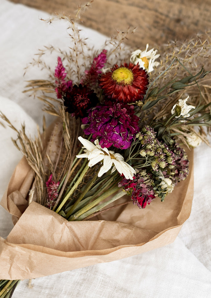 A dried flower bouquet in dark red and pink tones.