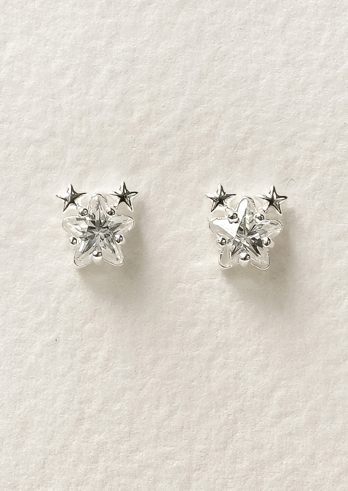 A pair of sterling silver star shaped cubic zirconia earrings with two tiny stars on the tops of each earring.