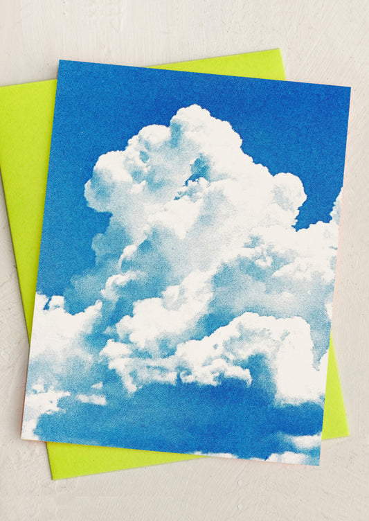 Card with a cloud design on a blue background, placed on a green envelope.