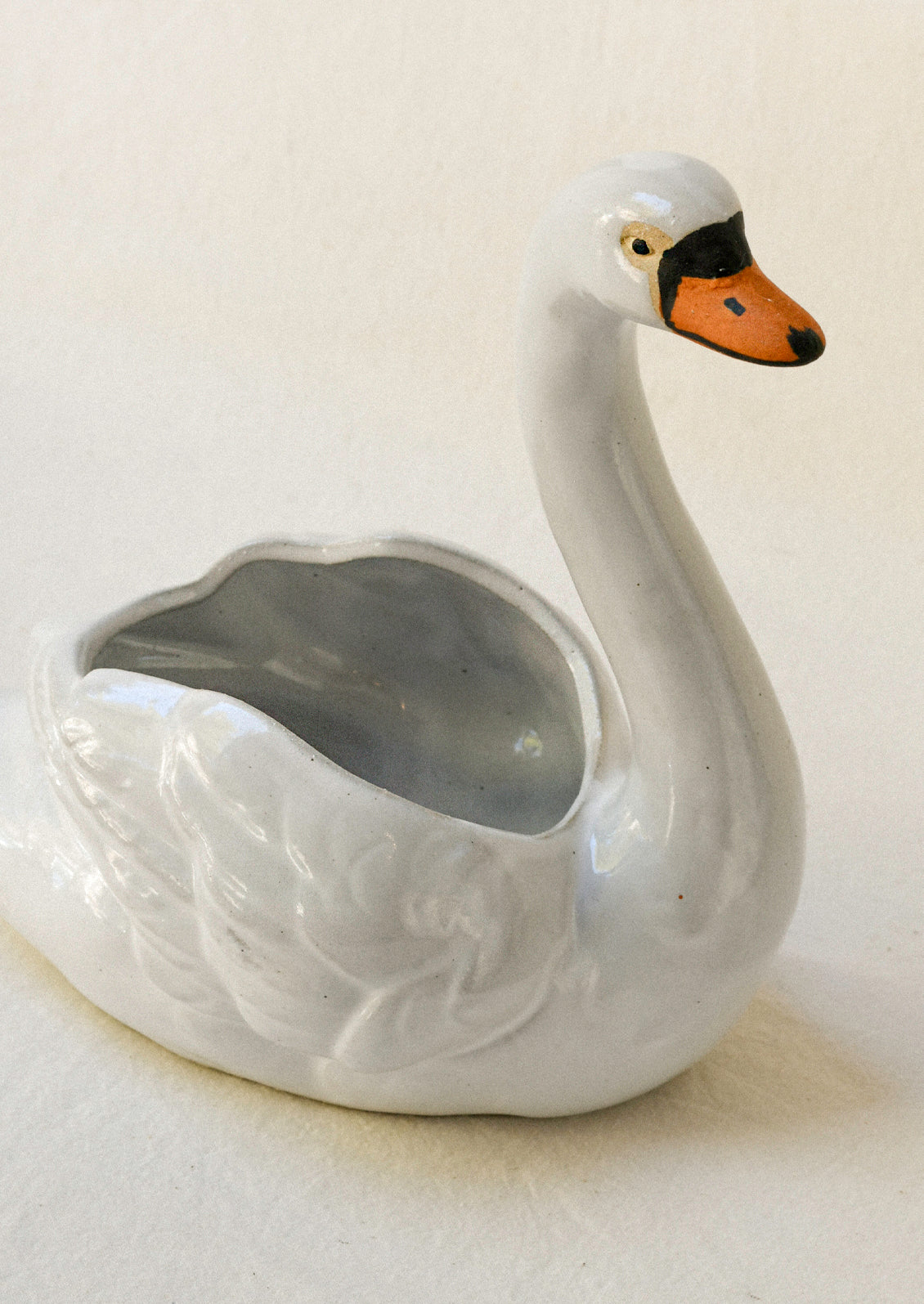 Top view of a ceramic planter in the shape of a cygnet sitting atop a table.