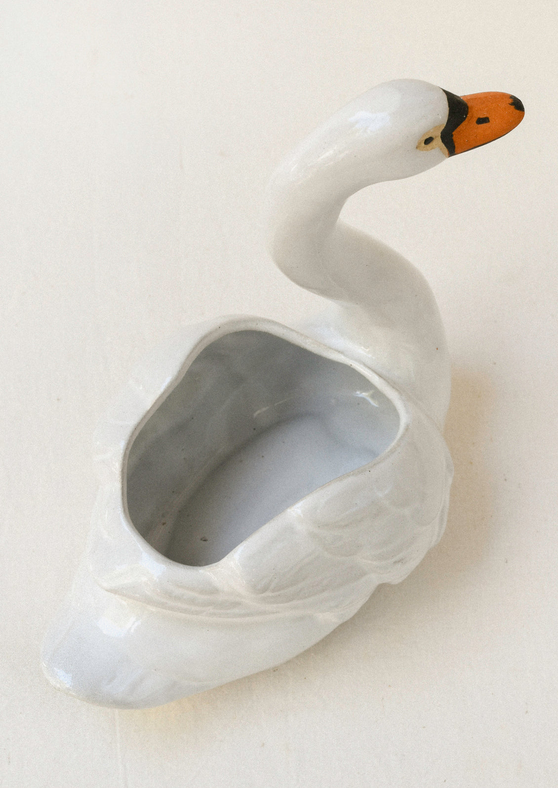 Top view of a ceramic planter in the shape of a cygnet sitting atop a table.