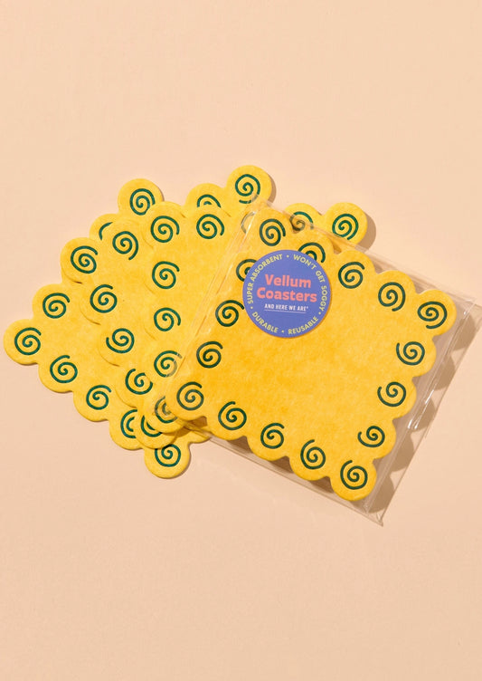 Yellow felt velum coasters with green spiral patterns, shown in a clear plastic bag.