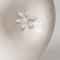 3: A glossy white ceramic vase with asymmetrical flower cutout detail.