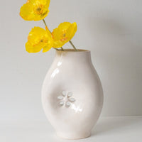 2: A glossy white ceramic vase with asymmetrical flower cutout detail.
