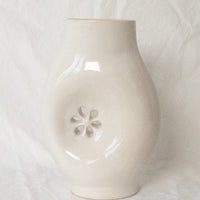 1: A glossy white ceramic vase with asymmetrical flower cutout detail.