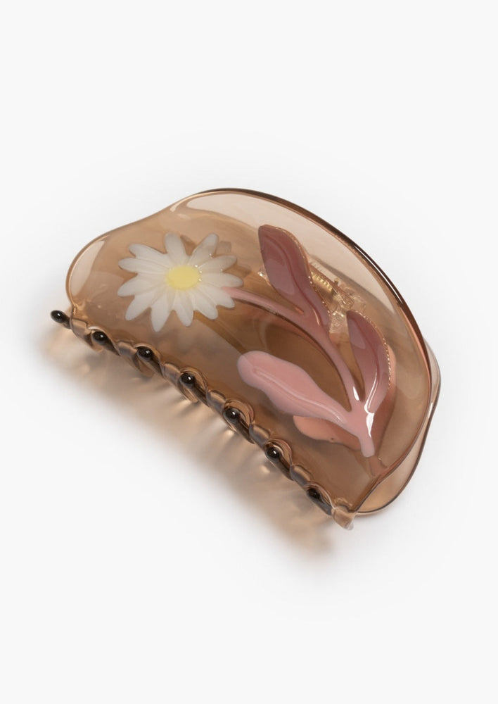 A transparent brown curved shape hair claw with daisy design.