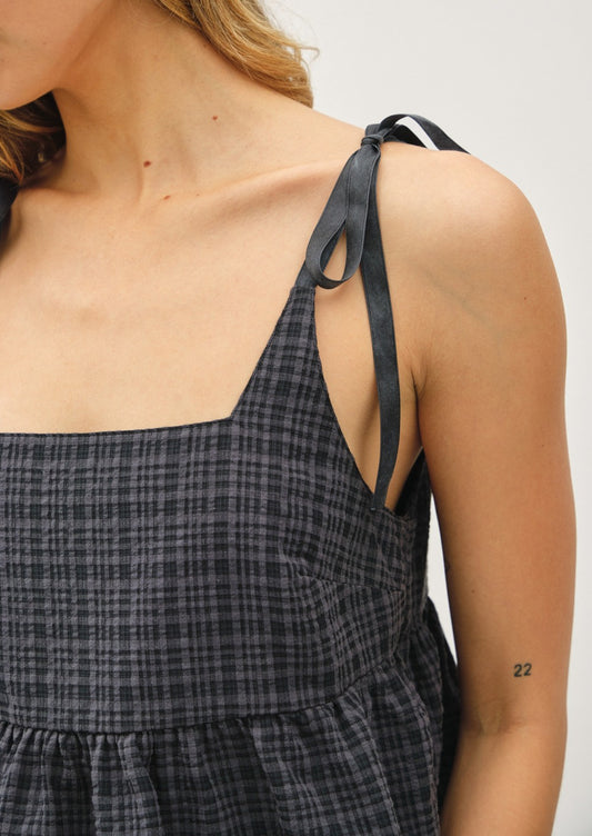 Close-up of a person wearing a black and white checkered dress with thin straps.