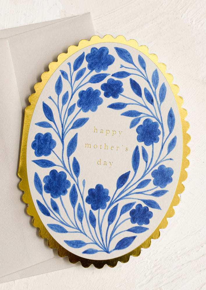 A blue floral print card with scalloped gold edges reading "Happy Mother's Day".