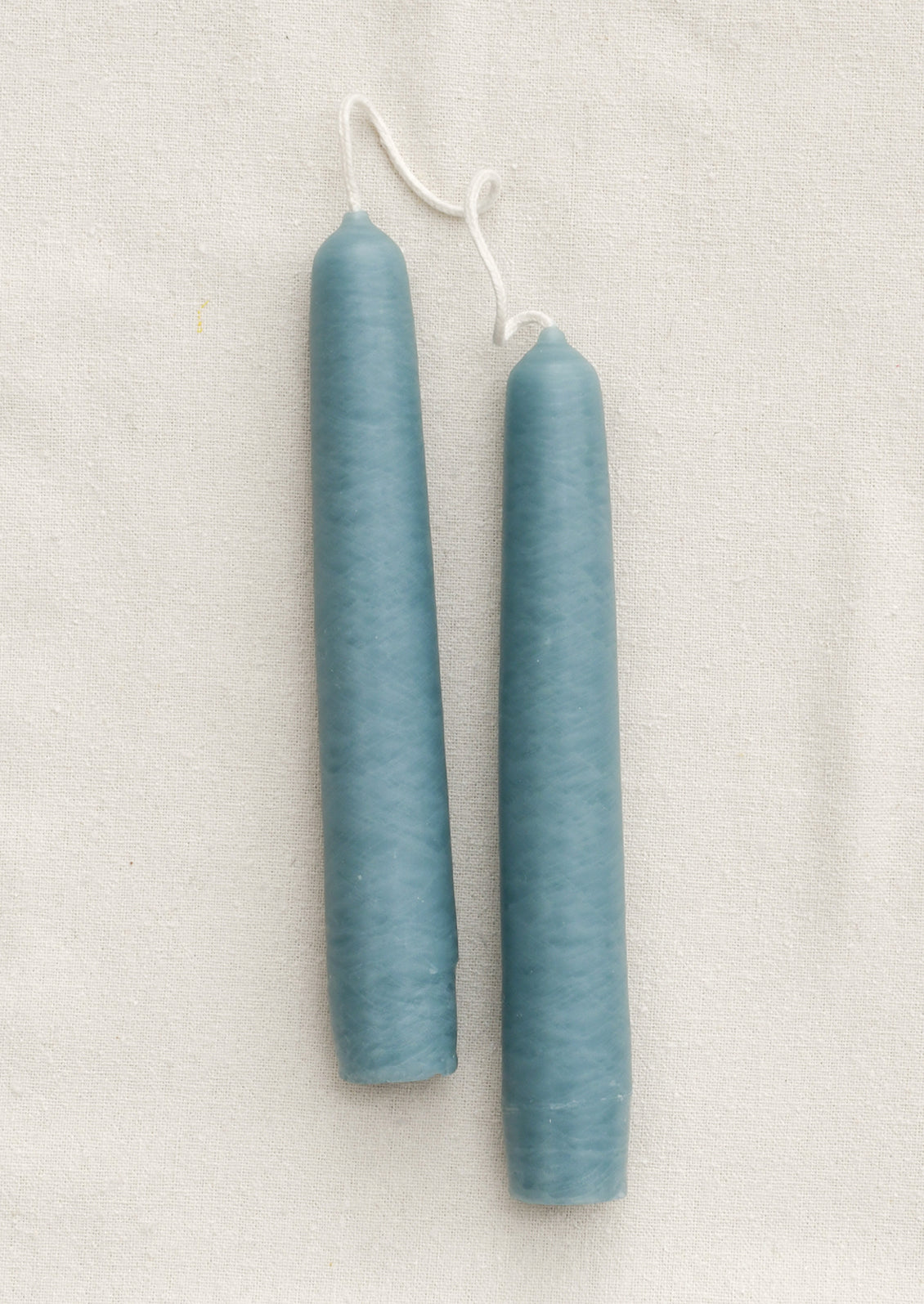 Two blue candles on a textured white surface