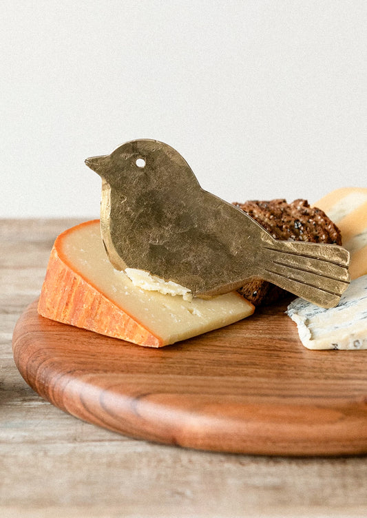 A brass cheese knife shaped like a bird.