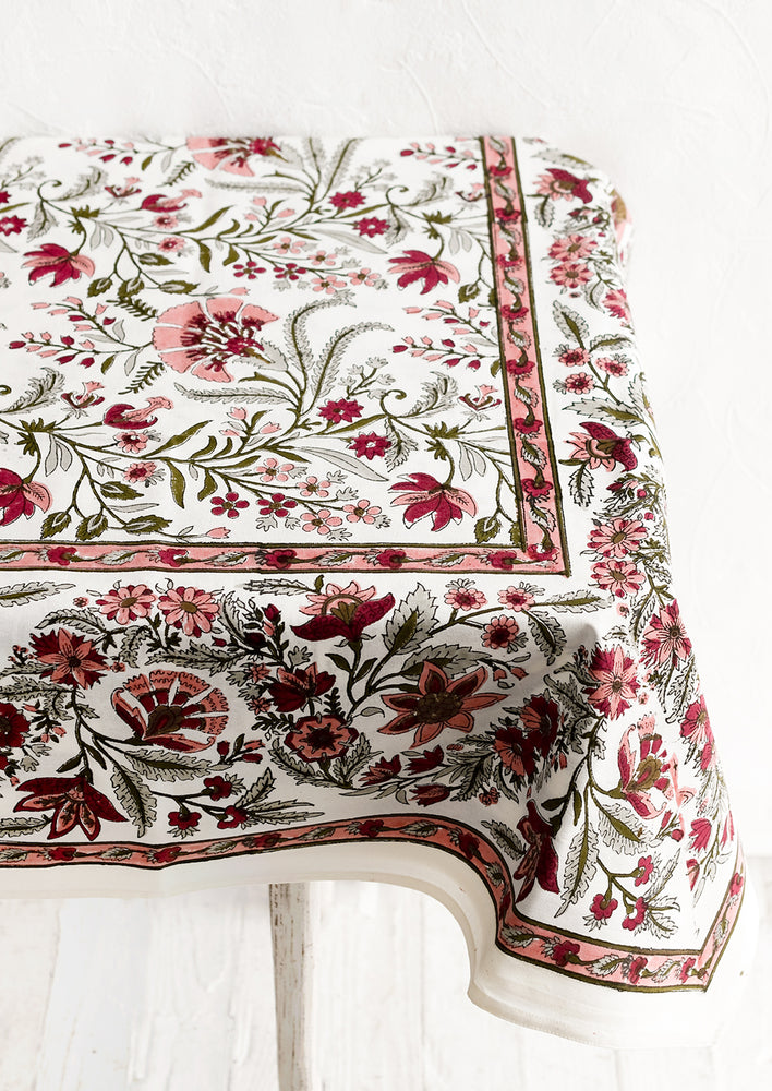 A block printed, floral patterned tablecloth in shades of pink and sage green.