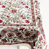 2: A block printed, floral patterned tablecloth in shades of pink and sage green.