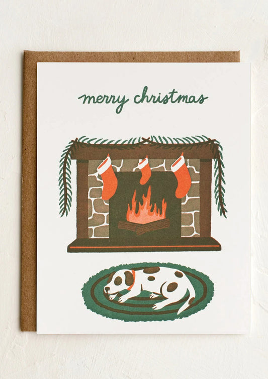 Christmas card with a fireplace, stockings, and a dog on a rug.