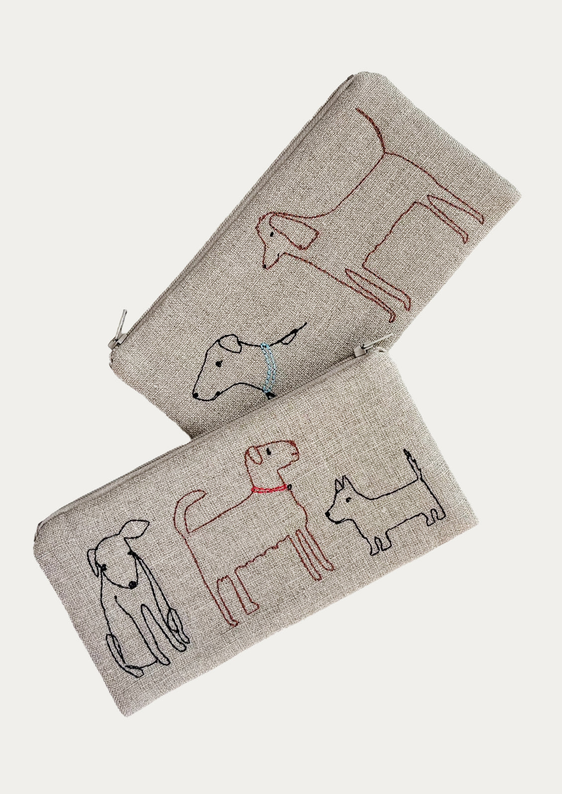 Two beige pouches with embroidered dog designs on a white background
