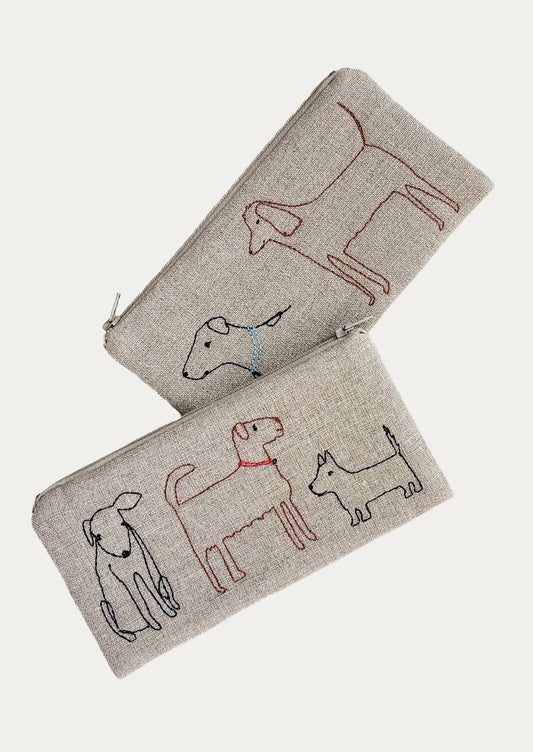 Two beige pouches with embroidered dog designs on a white background