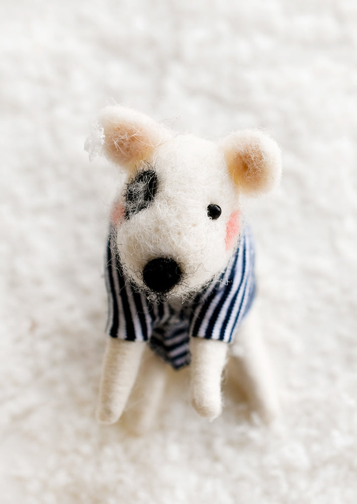 A felted holiday ornament of a white dog in a navy striped sweater.