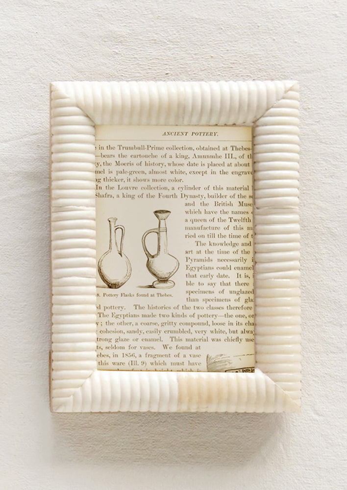 An ivory picture frame made of bone with puffy, ribbed border.