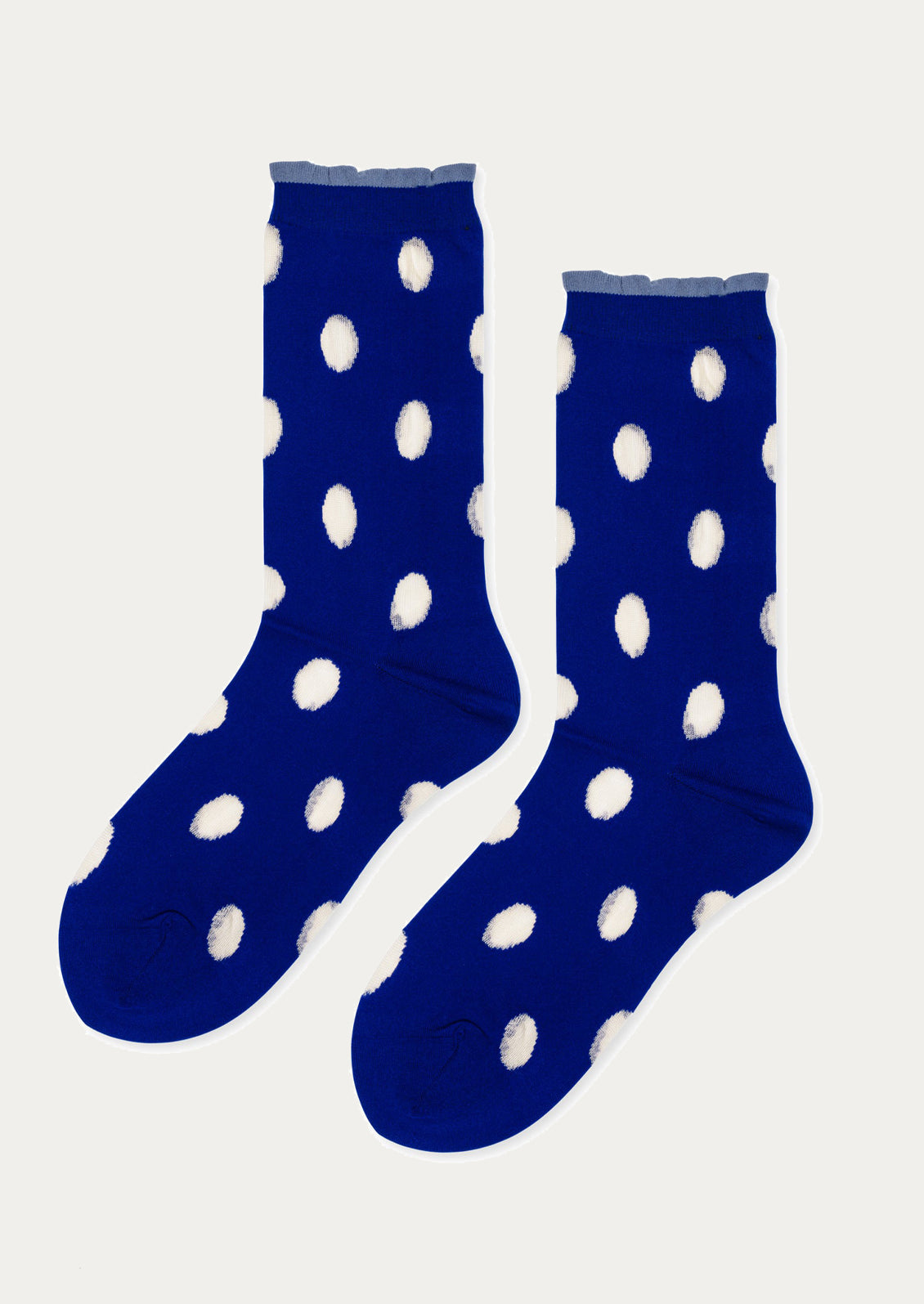 Pair of blue socks with white polka dots on a light gray background