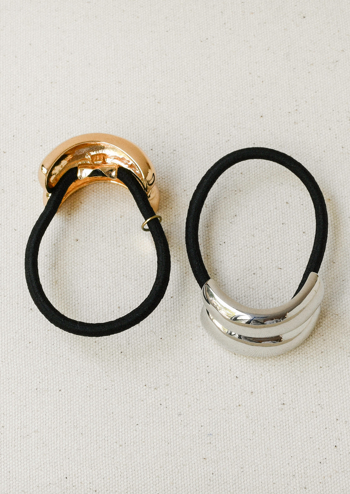 Black elastic hair ties with a gold and silver metal pendant with a double arch design.