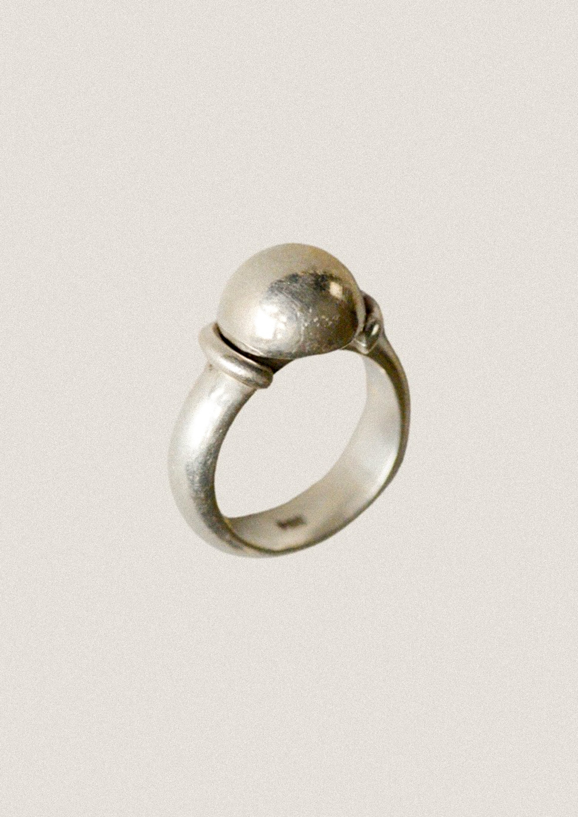 Silver ring with a spherical design on a light gray background