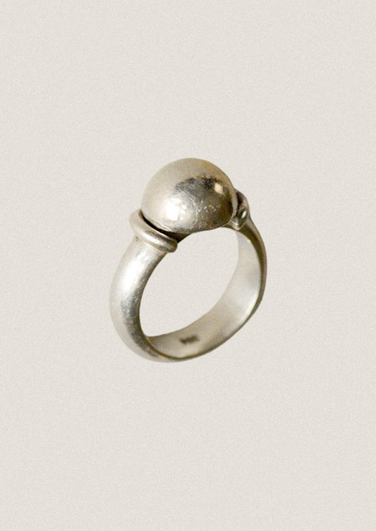 Silver ring with a spherical design on a light gray background