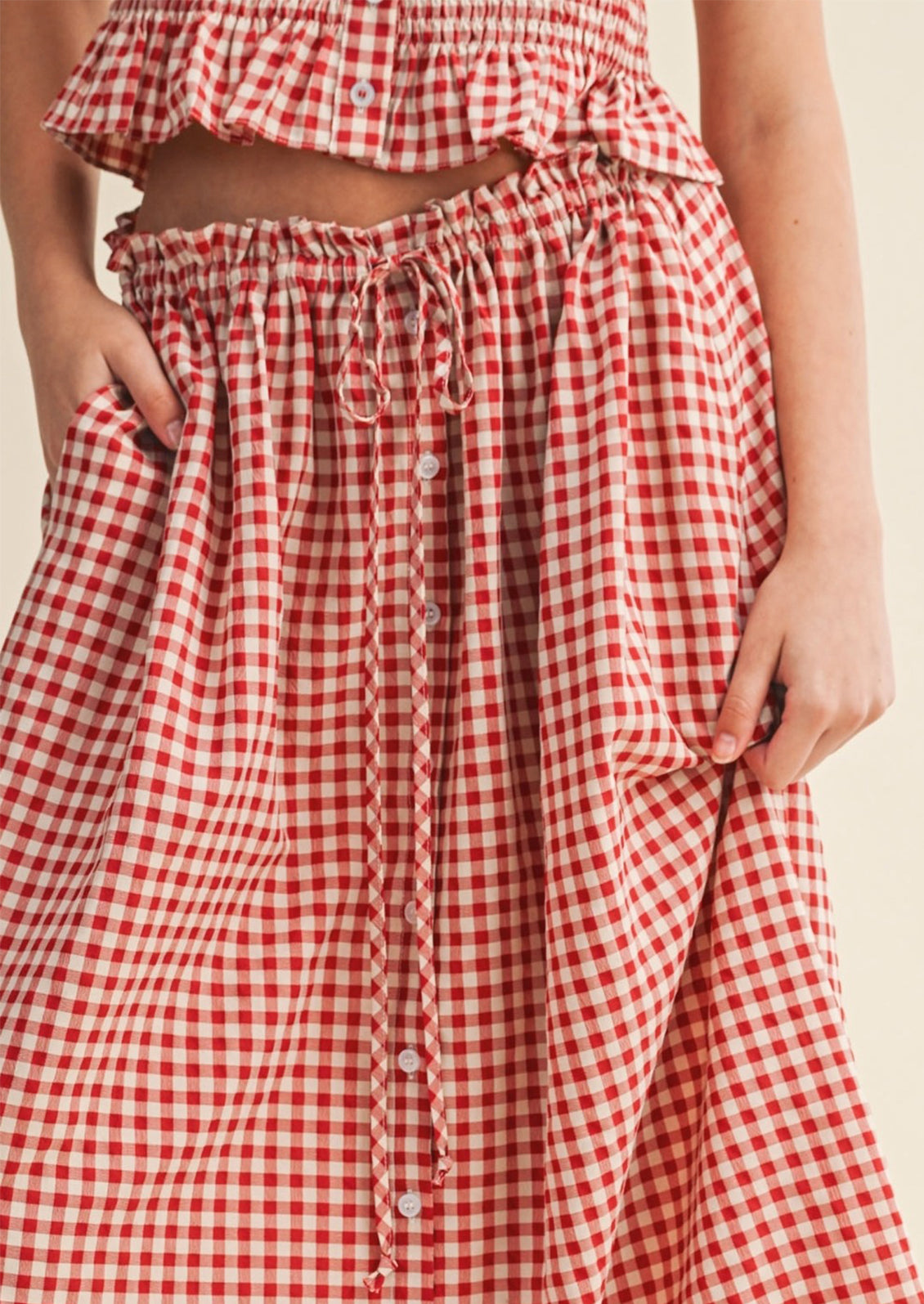 Red and white checkered skirt worn by a person on a beige background