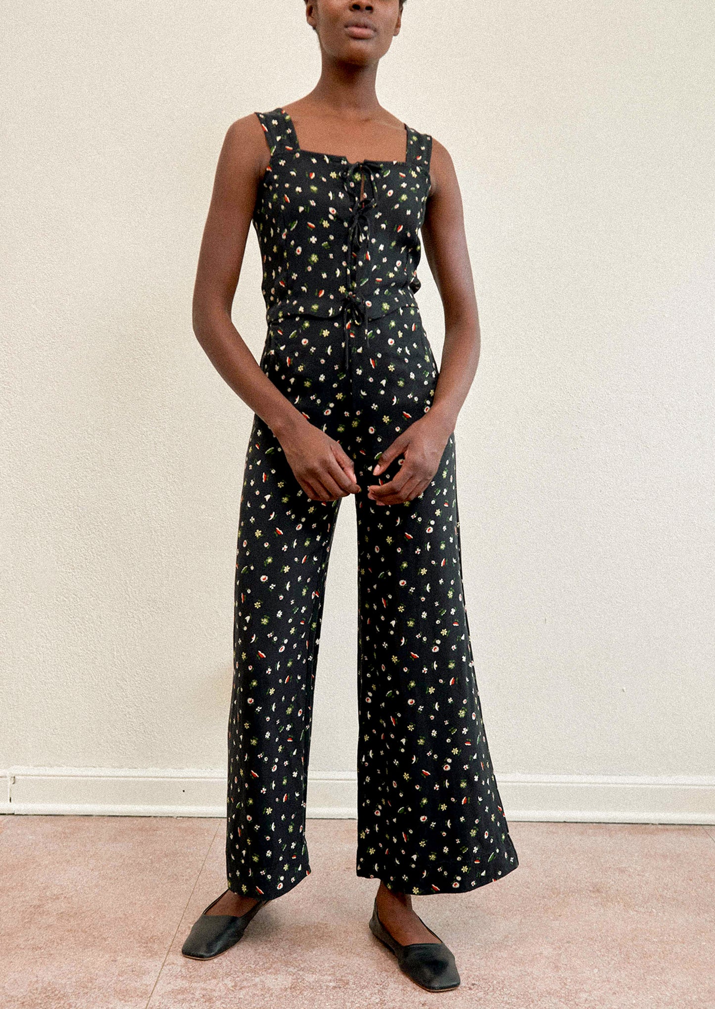A woman wearing a pair of high waisted pants in black with multicolor botanical print throughout.