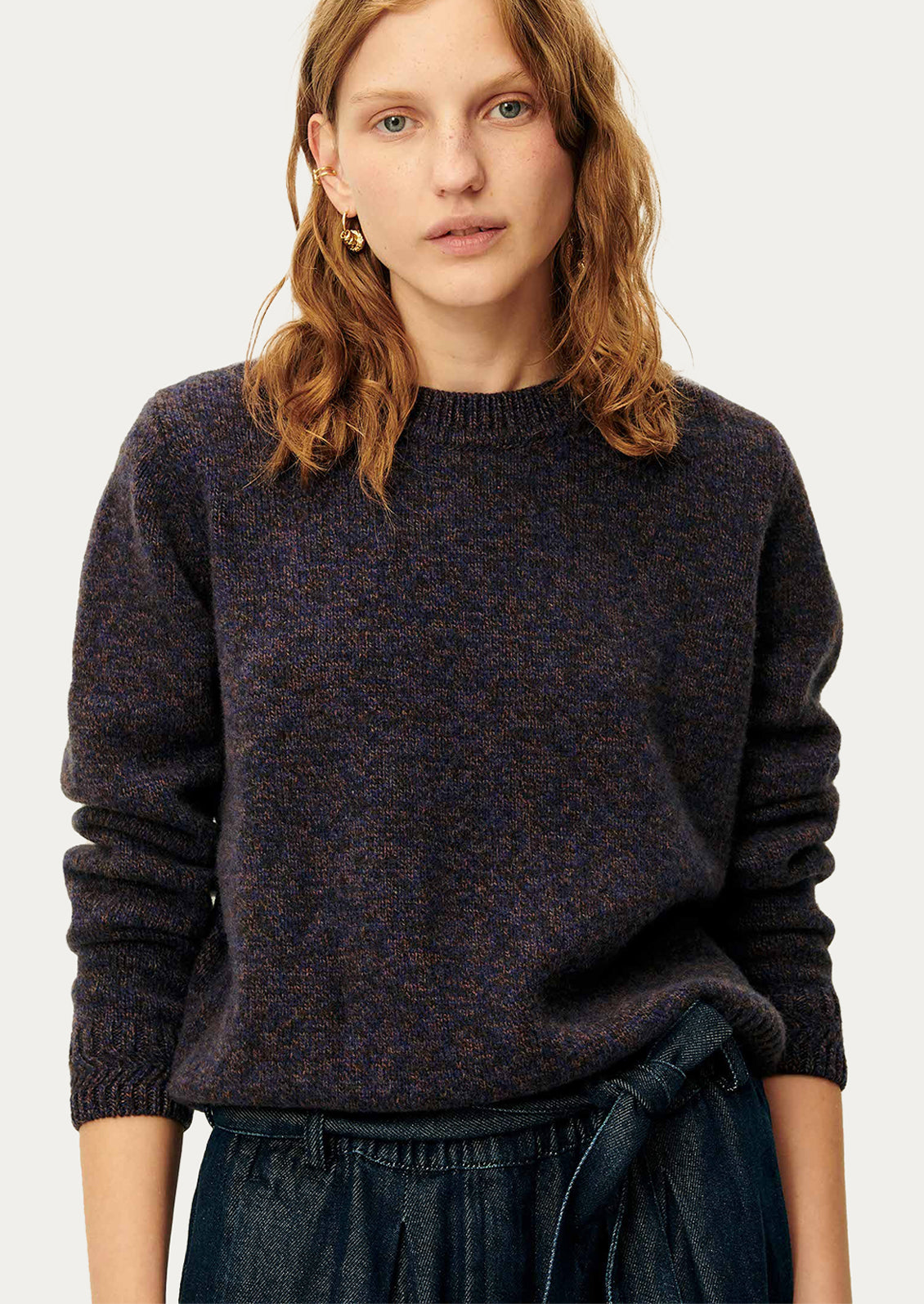 A woman wearing a dark sweater in ink blue melange yarn.