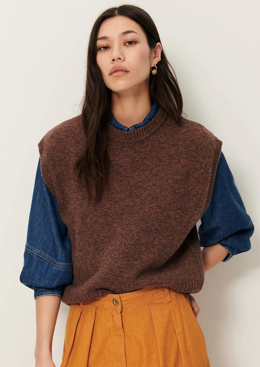 Woman wearing a brown knitted vest over a blue shirt.