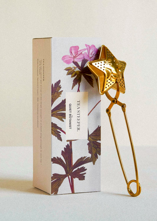 A brass tea steeper with star shaped end with smiling face.