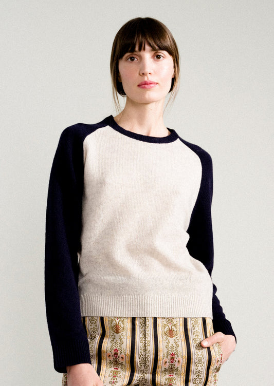 A woman wearing a raglan sweater in light grey and navy.