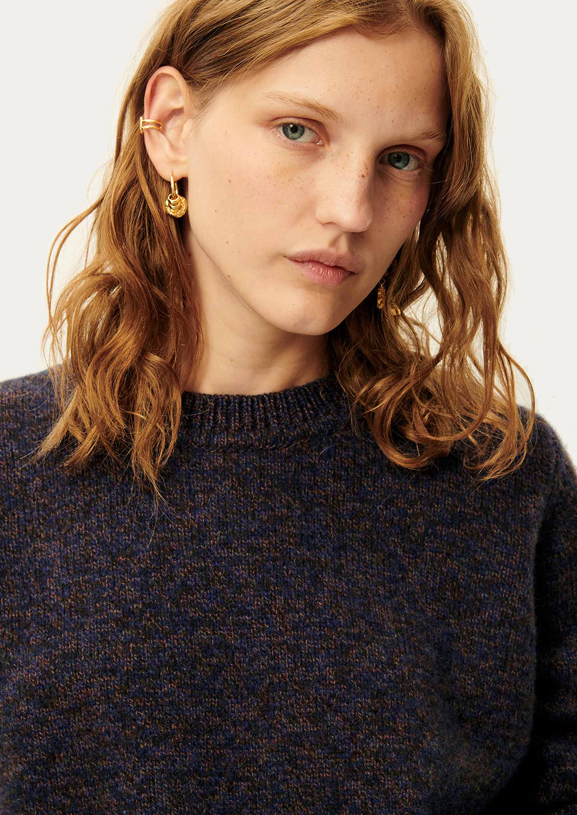 A woman wearing a dark sweater in ink blue melange yarn.