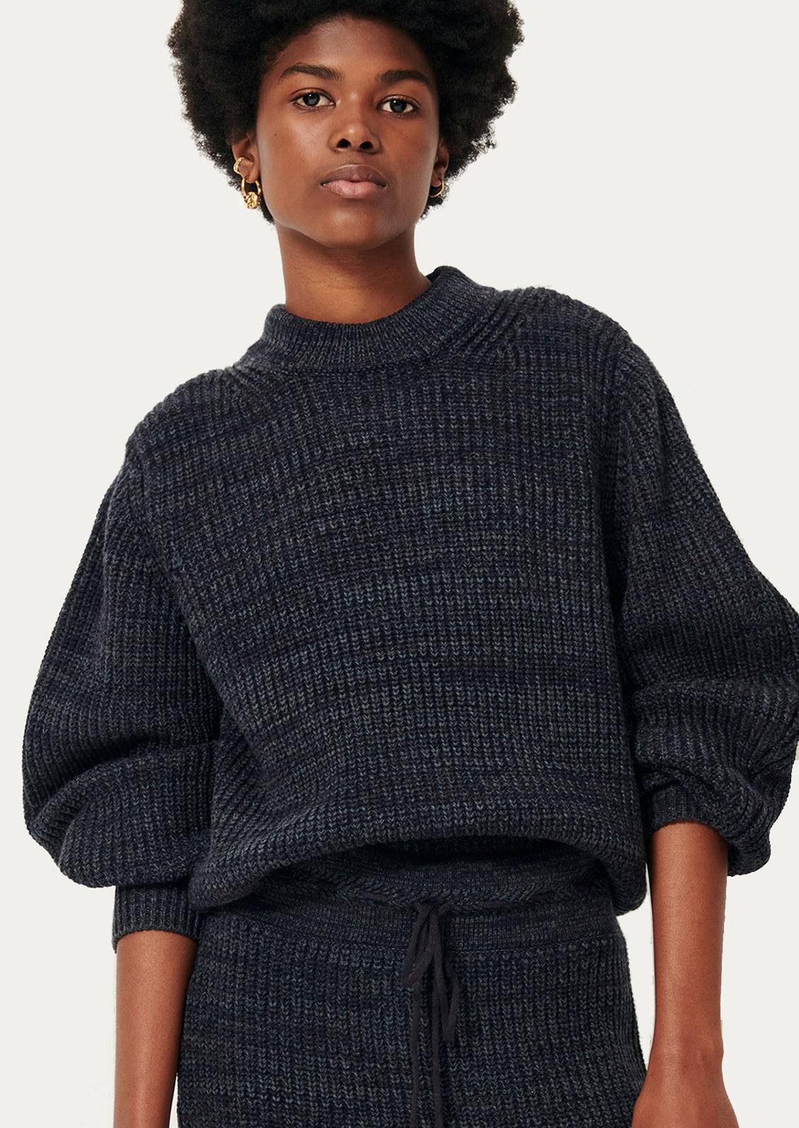 Person wearing a dark gray textured sweater and pants.