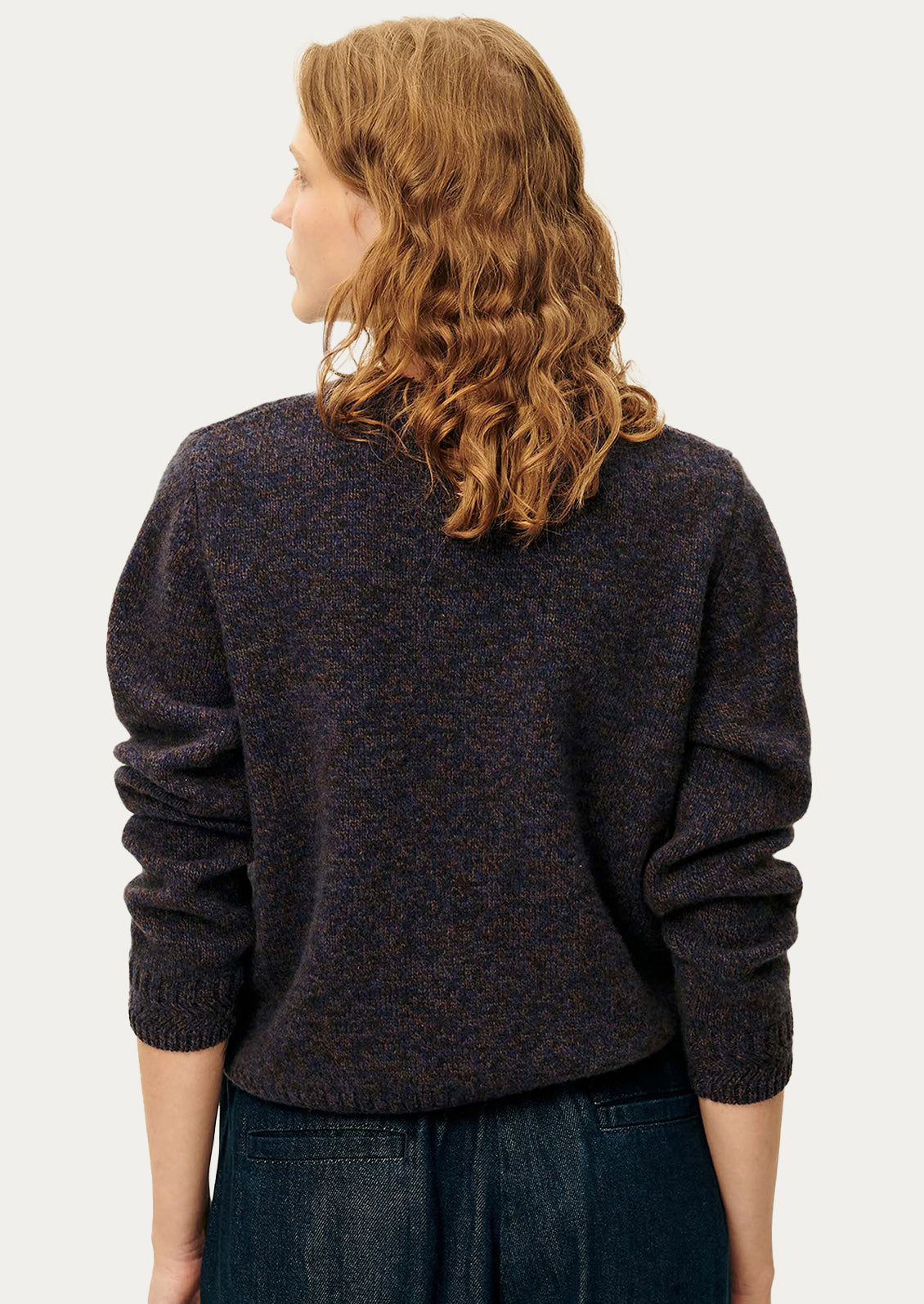 A woman wearing a dark sweater in ink blue melange yarn.