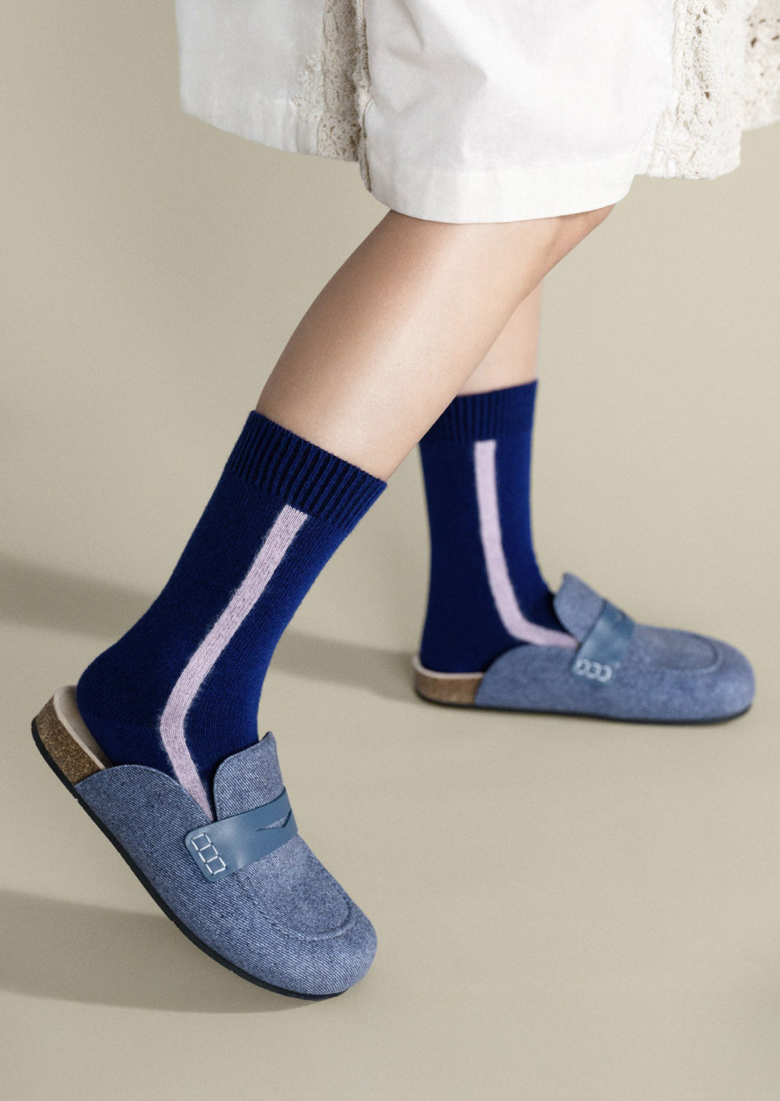 A pair of navy blue cashmere socks with single vertical lilac stripe.