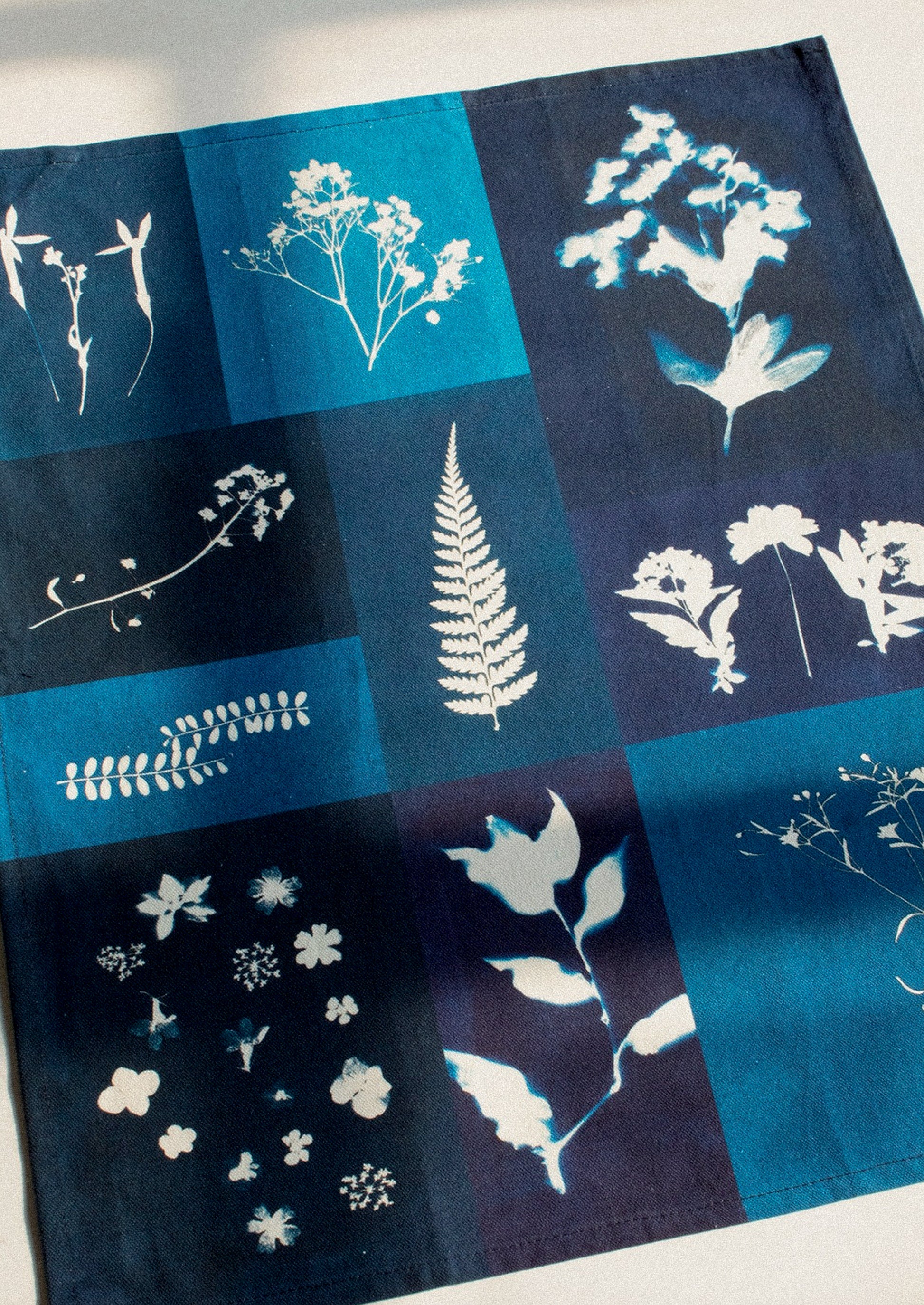 Tea towel with printed white botanical designs on a blue background