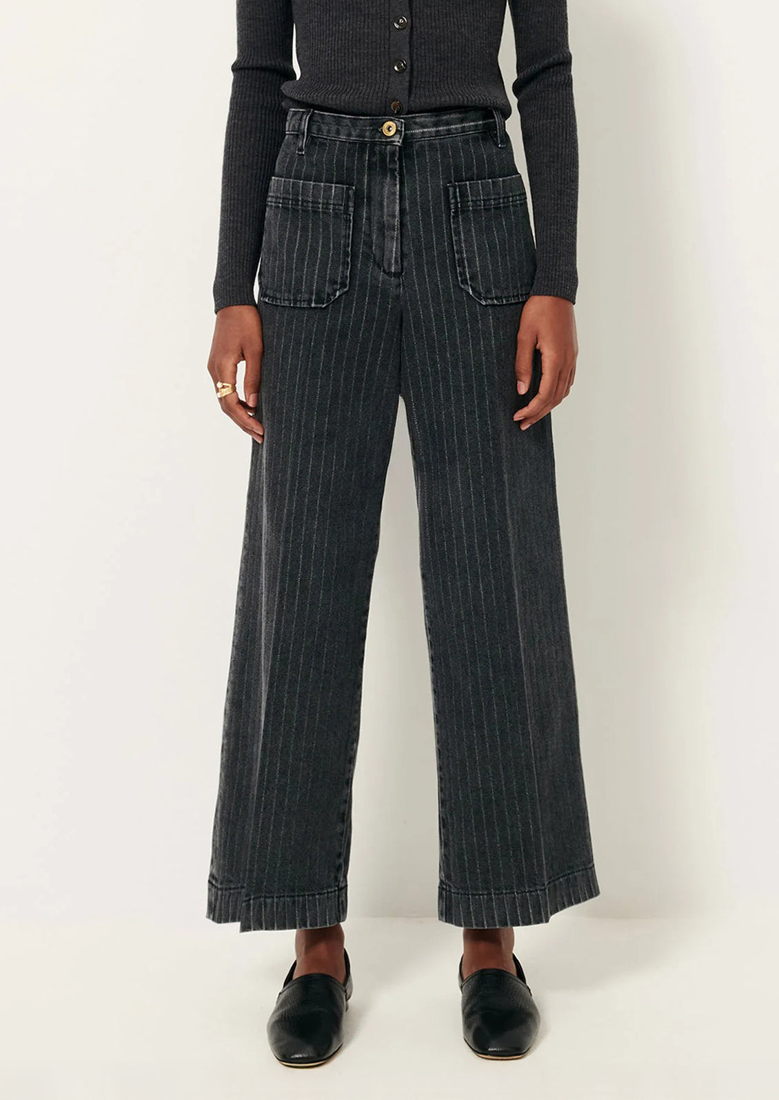 A person wearing a pair of wide leg jeans in charcoal pinstripe denim.