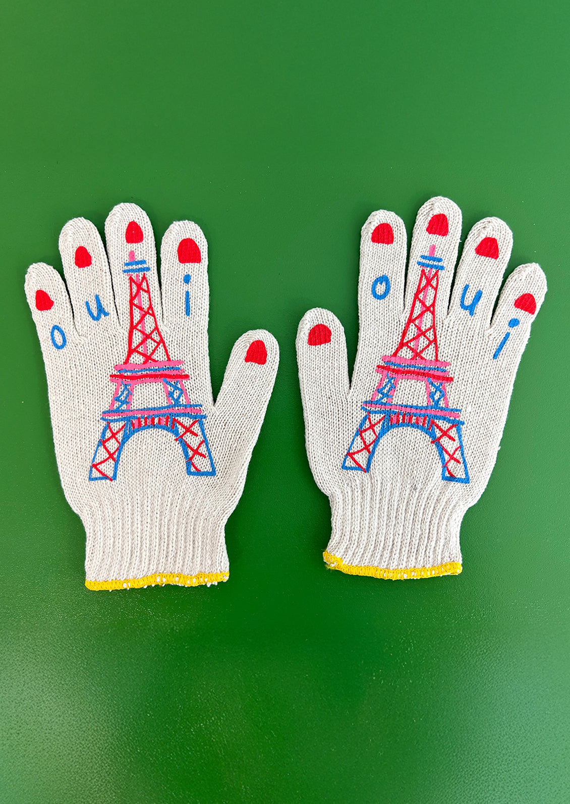 Pair of gloves with Eiffel Tower design on a green background