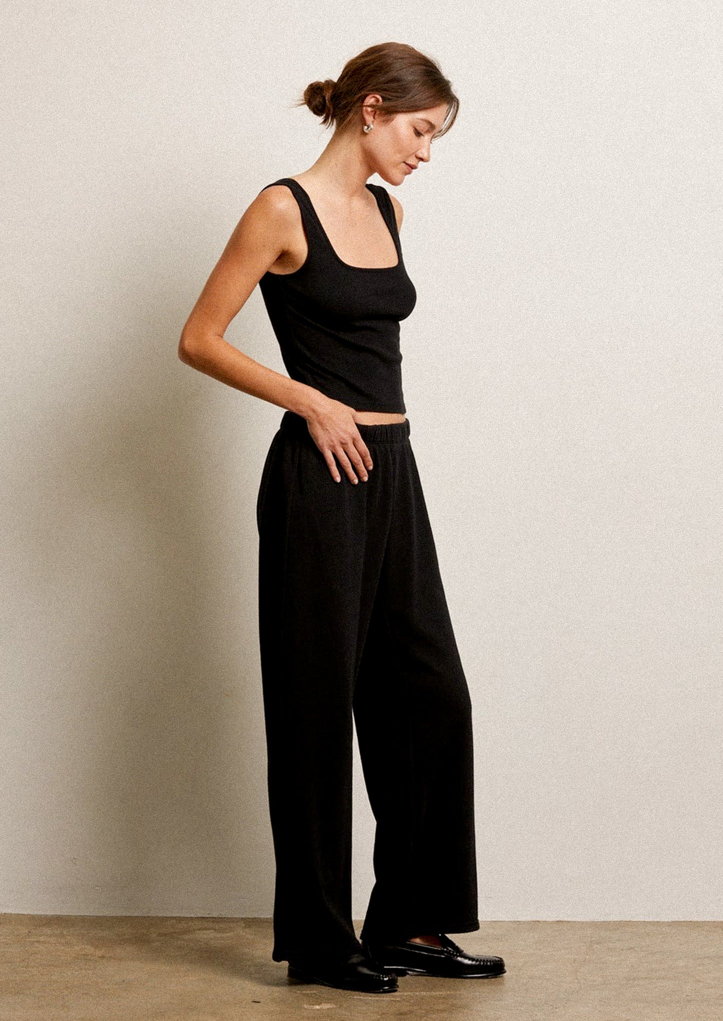 Woman wearing a black sleeveless top and black wide-leg pants.
