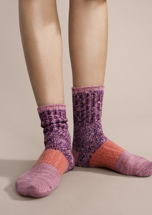 A person wearing a pair of cotton socks in pink melange colorway.