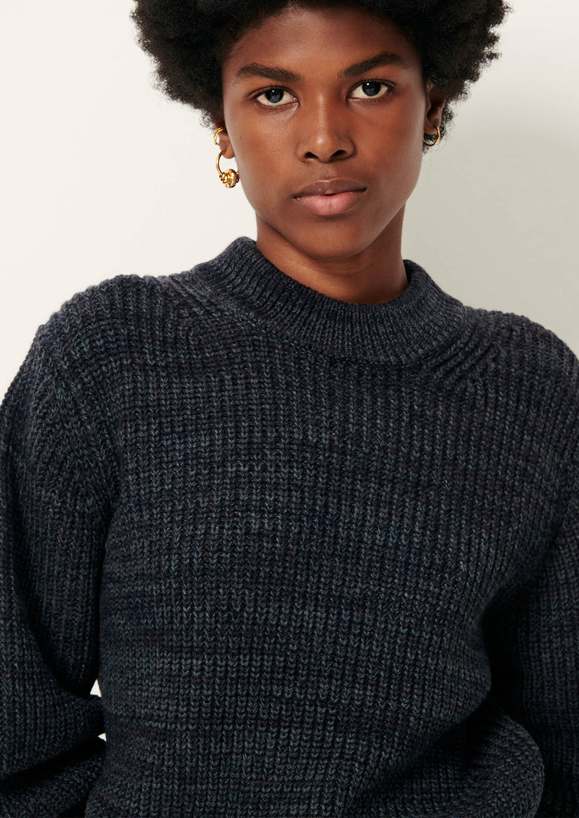 Person wearing a dark gray textured sweater and pants.