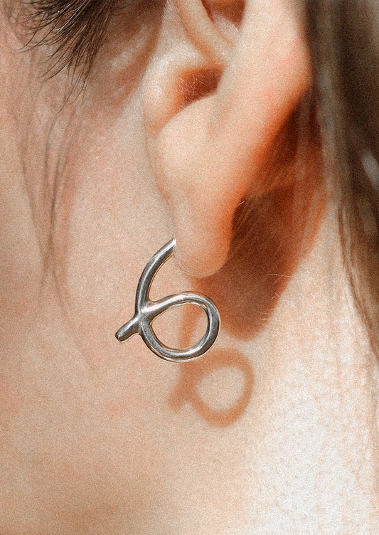 A person wearing a loop shaped sterling silver stud earring.
