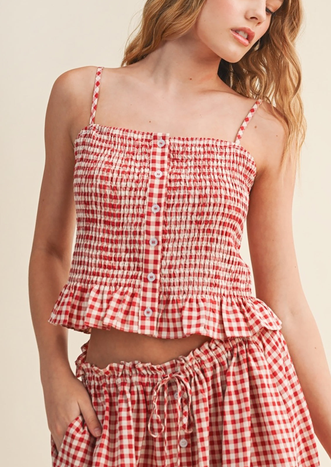 Red and white checkered top and skirt set on a model against a beige background