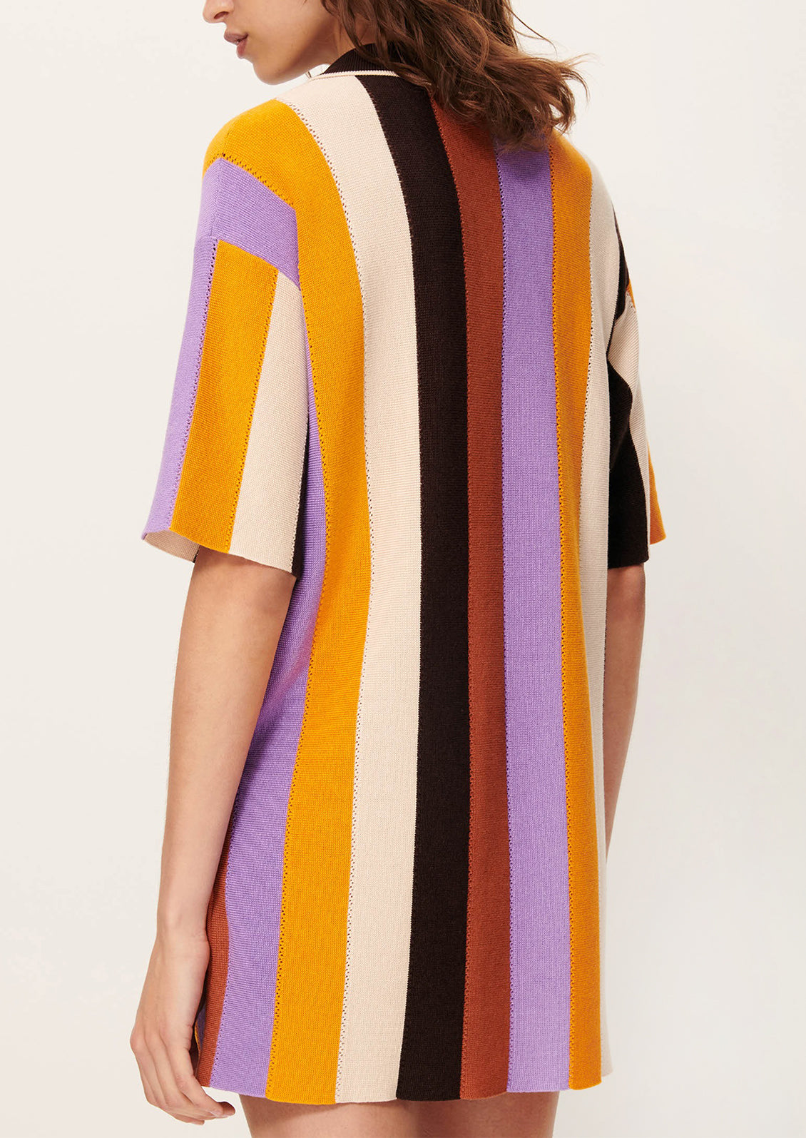 A woman wearing a colorful striped polo dress with short sleeves.