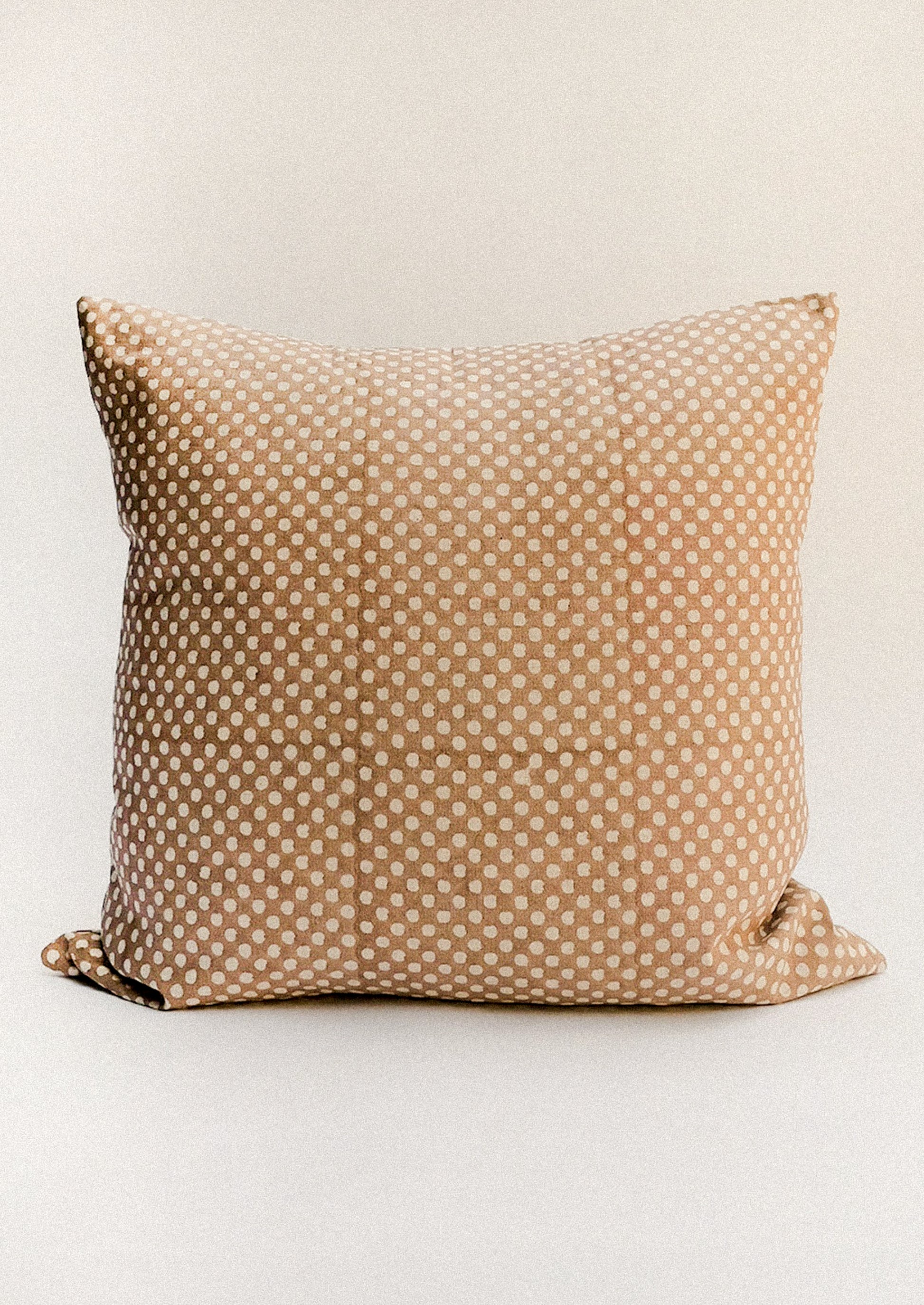 A brown throw pillow with contrast polka dot pattern.